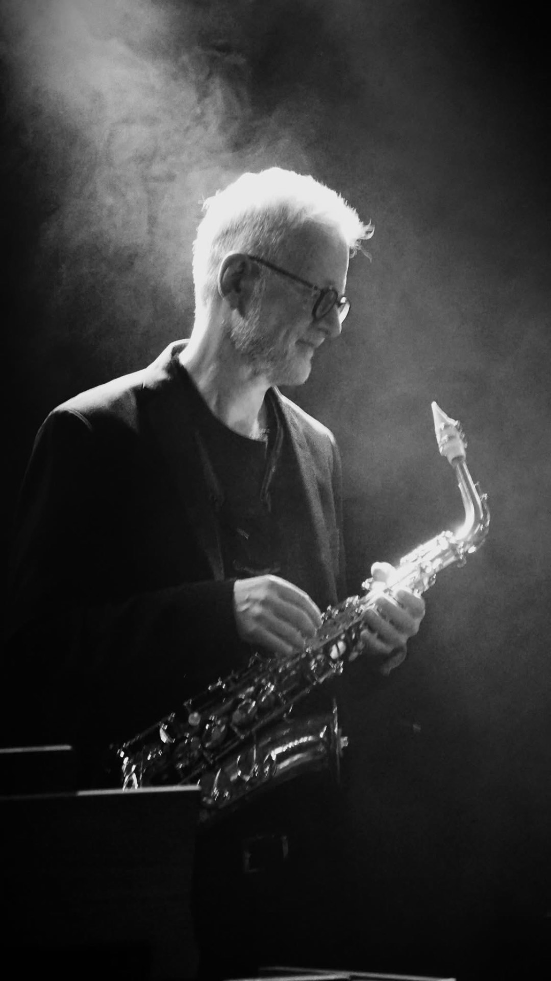 Ulli Jünemann spielt Altsaxophon im Bühnenlicht, atmosphärische Schwarzweiß-Aufnahme